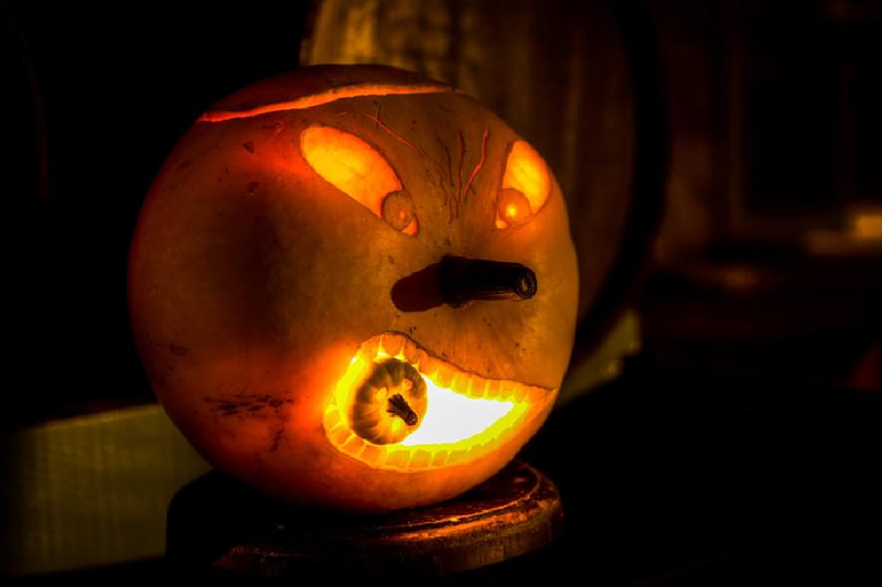 A carved lit pumpkin in a dark room
